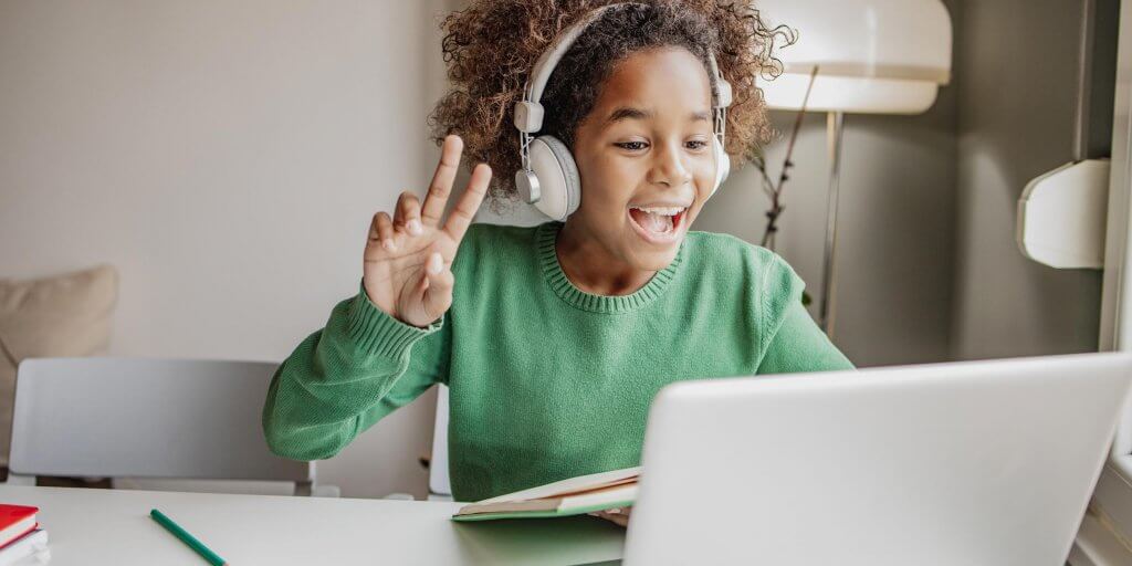 A young person smiling while using a laptop to celebrate Digital Learning Day.
