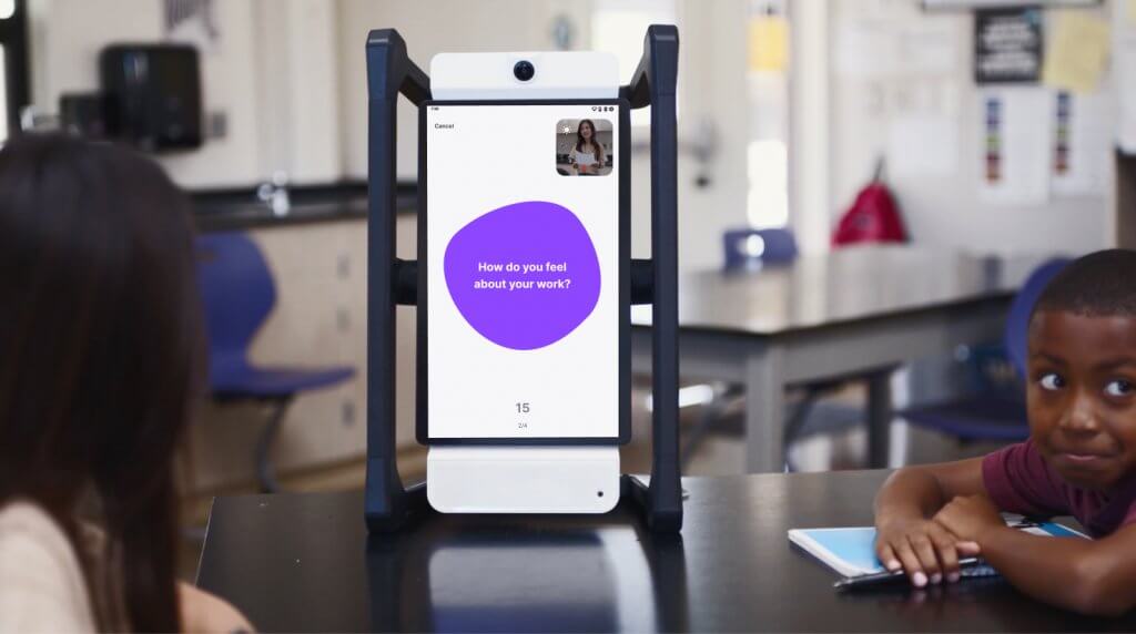 Students in a classroom setting sit in front of Swivl's Mirror, an automated reflection tool, during an engagement reflection. The screen on Mirror reads, "How do you feel about your work?"