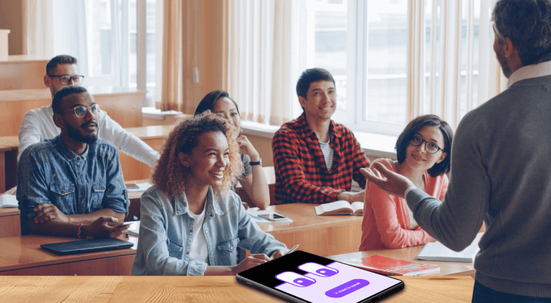Teacher leading an engaged classroom discussion while students participate attentively, with a tablet showing the M2talk participation interface in the foreground.