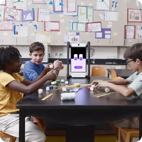 Three students working together to build a structure using spaghetti and marshmallows, with M2