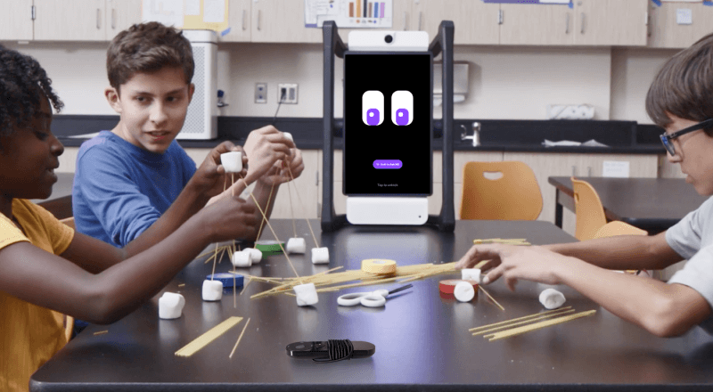 Three students working together to build a structure using spaghetti and marshmallows, with M2