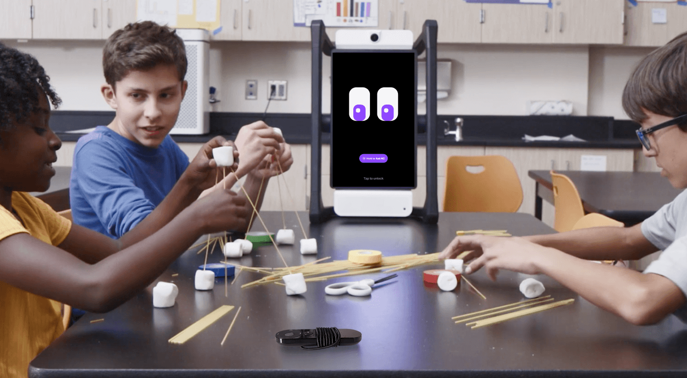 Three students working together to build a structure using spaghetti and marshmallows, with M2